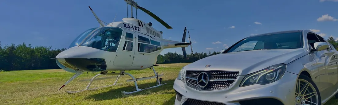 Helicóptero Bell 206 junto a un automóvil ejecutivo en un campo